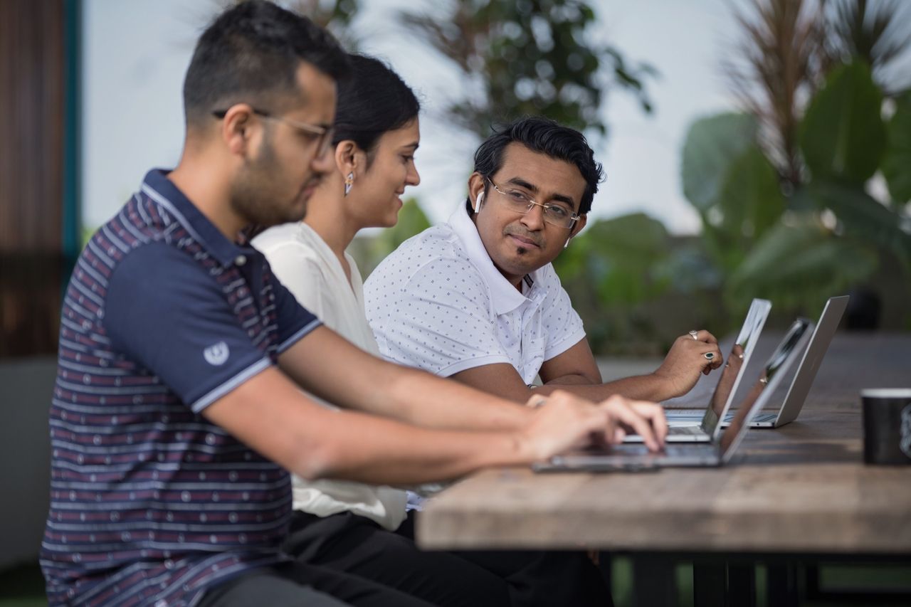 Drie collega’s overleggen aan een tafel met laptops